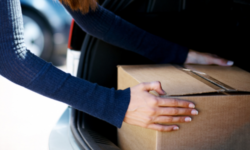 Woman putting a cardboard box in trunk